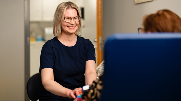 Bioanalyytikko Päivi ottaa asiakkaalta hymyillen näytettä
