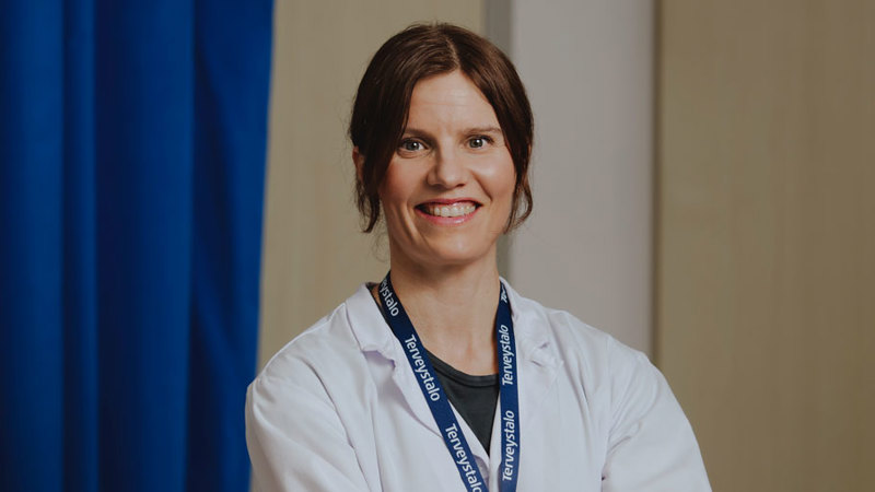 Gynekologi Maria Tuominen vastaanottohuoneessa lääkärintakki yllään.