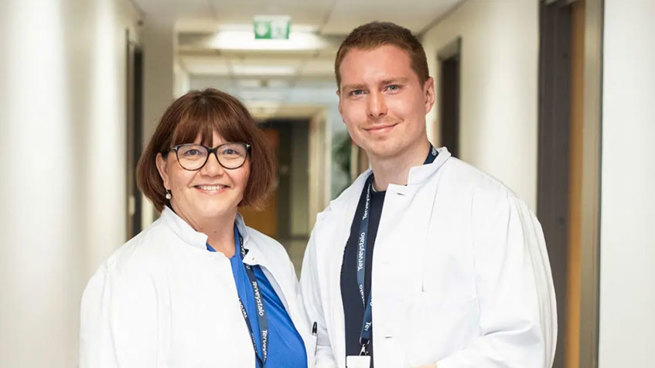 Yleislääkärit Marja-Leena Hyypiä ja Arttu Seppänen vastaanoton käytävällä hymyillen.