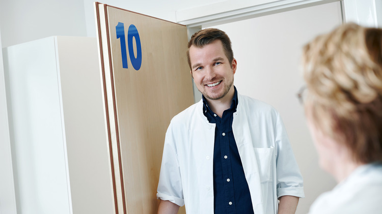 Kolme lääkäriä ja hoitaja jutustelevat vastaanoton käytävällä.
