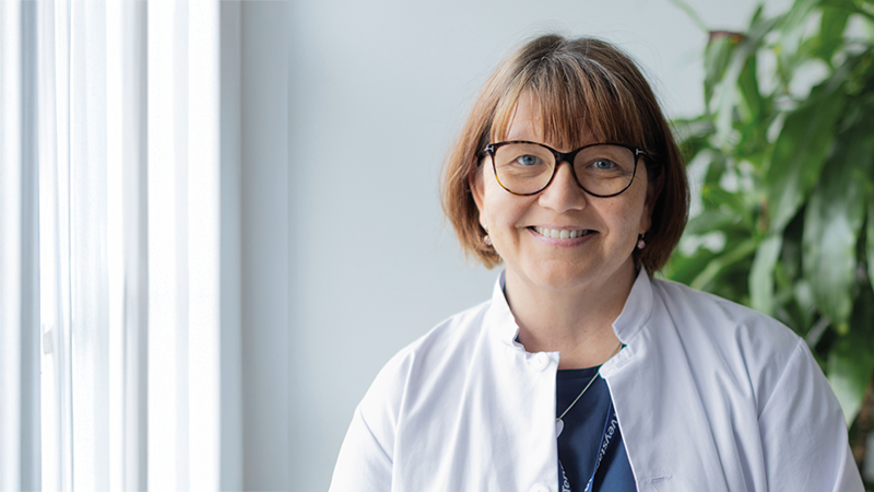 Hymyilevä työterveyslääkäri Nina Salmela vastaanoton käytävällä