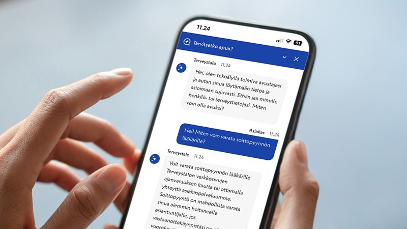 Henkilöllä on kädessään matkapuhelin, jossa on auki Terveystalon tekoälyavustaja