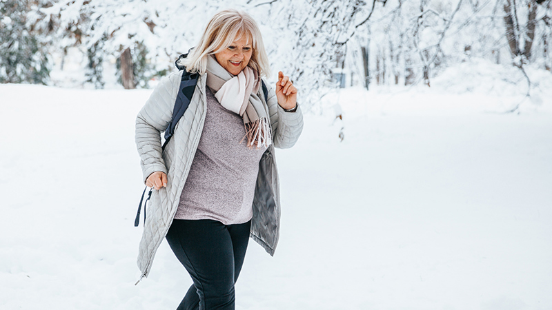Nainen lenkkeilee iloisena lumihangessa