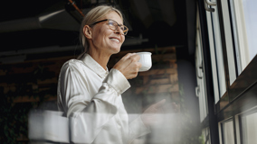 Nainen juo kahvia ja katsoo ulos ikkunasta