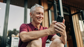 Kuva, jossa aikuinen mies katsoo puhelintaan ja hymyilee.