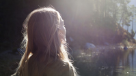 Nainen katselee aurinkoista metsämaisemaa ?? ''