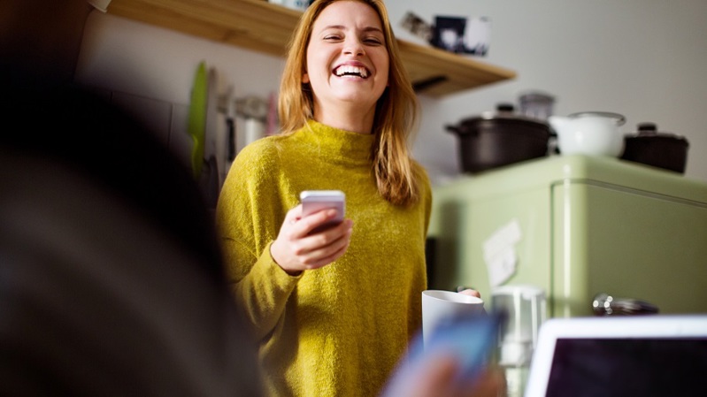 Nainen hymyilee kahvikuppi kädessä