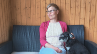 Paula Reponen istuu sohvalla koira sylissään ?? ''