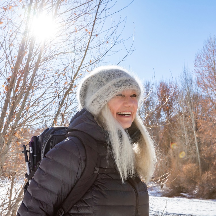 Seniorinainen hymyilee aurinkoisella ilmalla talvella