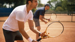 Kaksi miestä pelaamassa tennistä.
