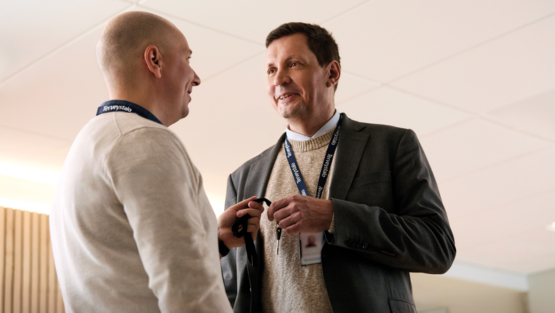 Sami Lepp&auml;m&auml;ki puvuntakki p&auml;&auml;ll&auml; juttelemassa vastaanottohuoneen k&auml;yt&auml;v&auml;ll&auml; kollegan kanssa avaimet k&auml;dess&auml;.